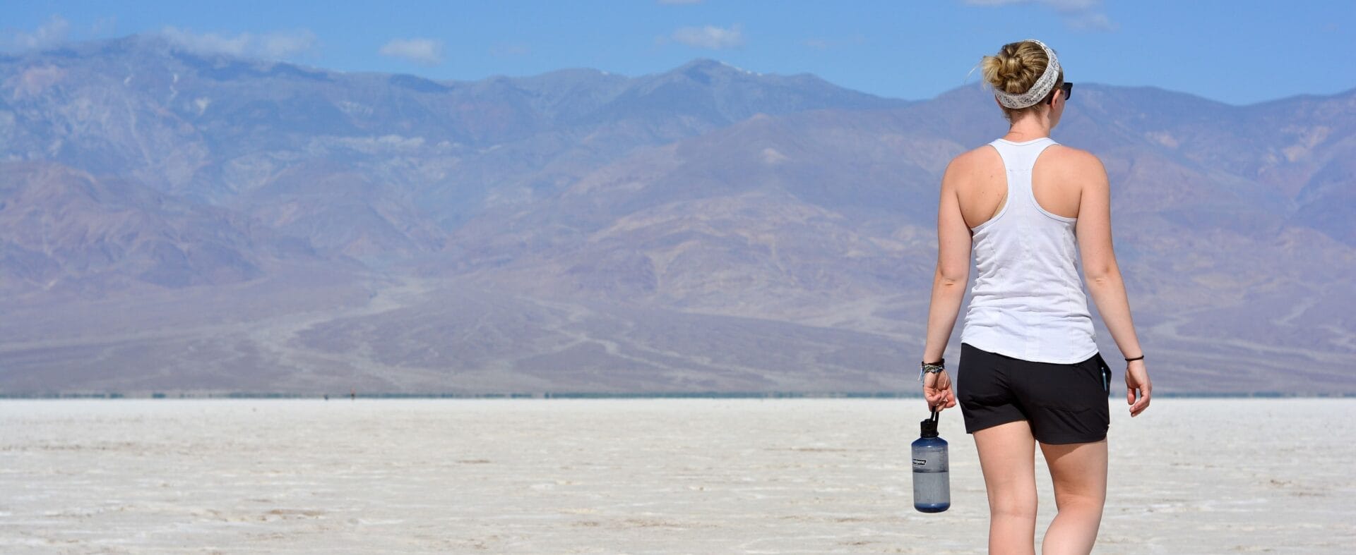 Frau mit Flasche in der Hand in der Wüste