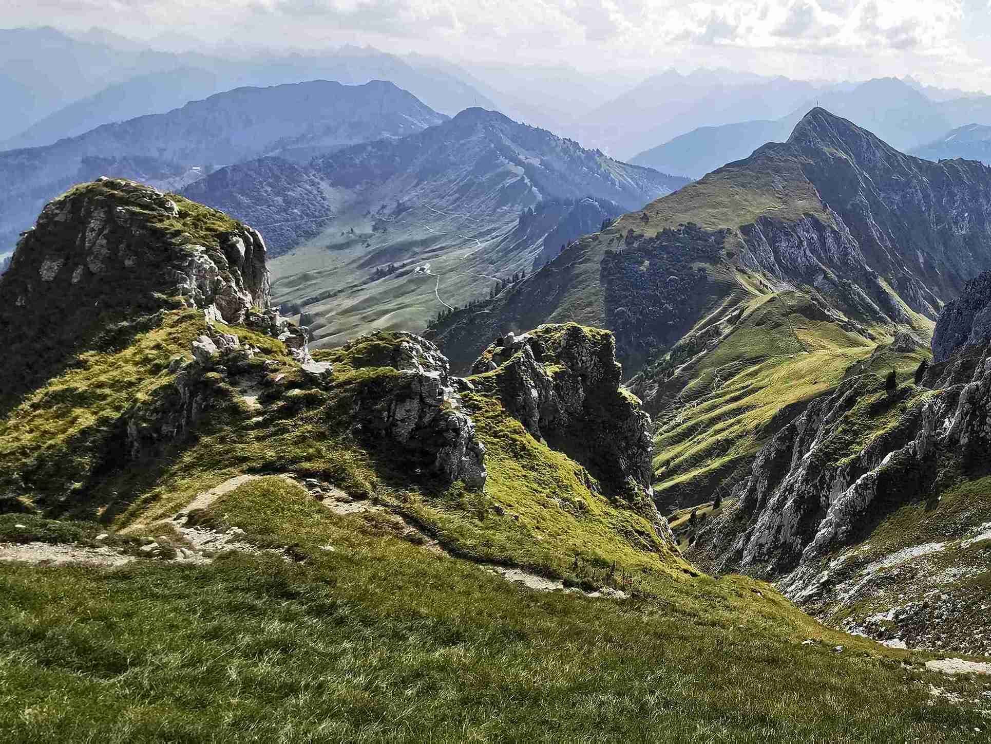 Alpenpanorama der Tannheimer Berge mit grünen Wiesen und felsigen Berggipfeln bei klarem Wetter
