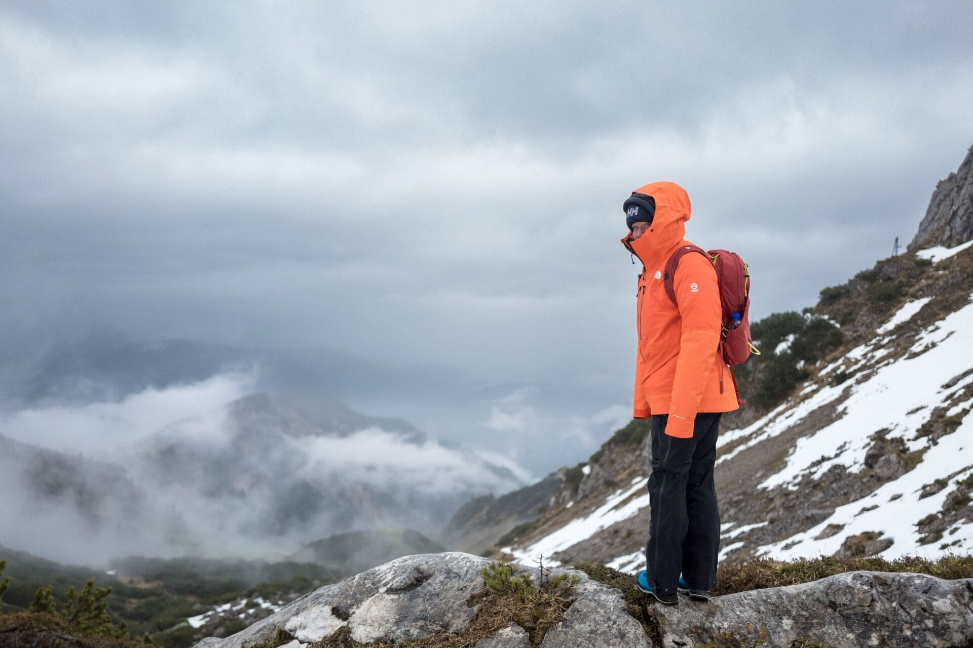 Wolkenverhangene Berglandschaft mit Frau im Vordergrund.