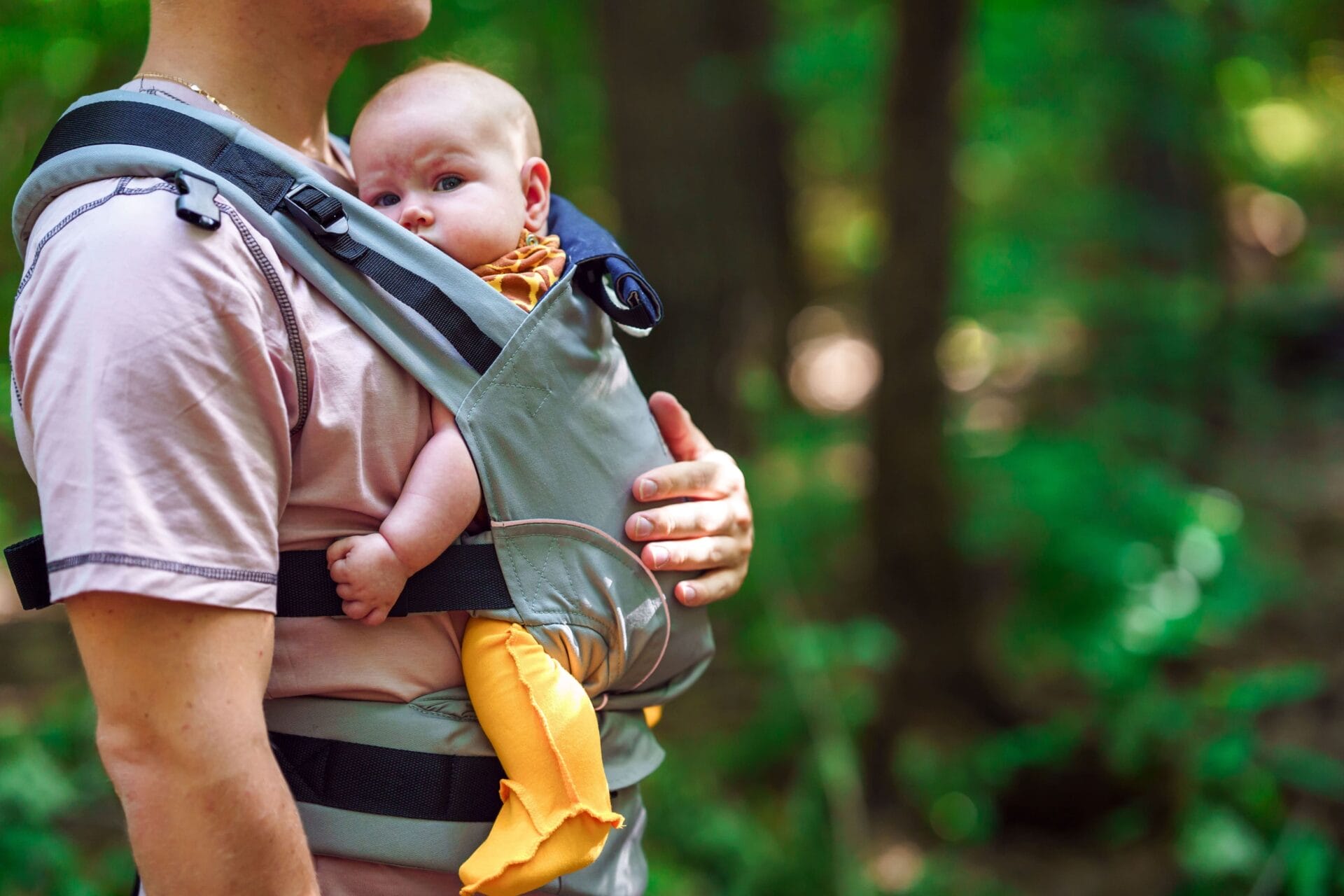 Mann tägt ein Baby auf seinem Bauch.