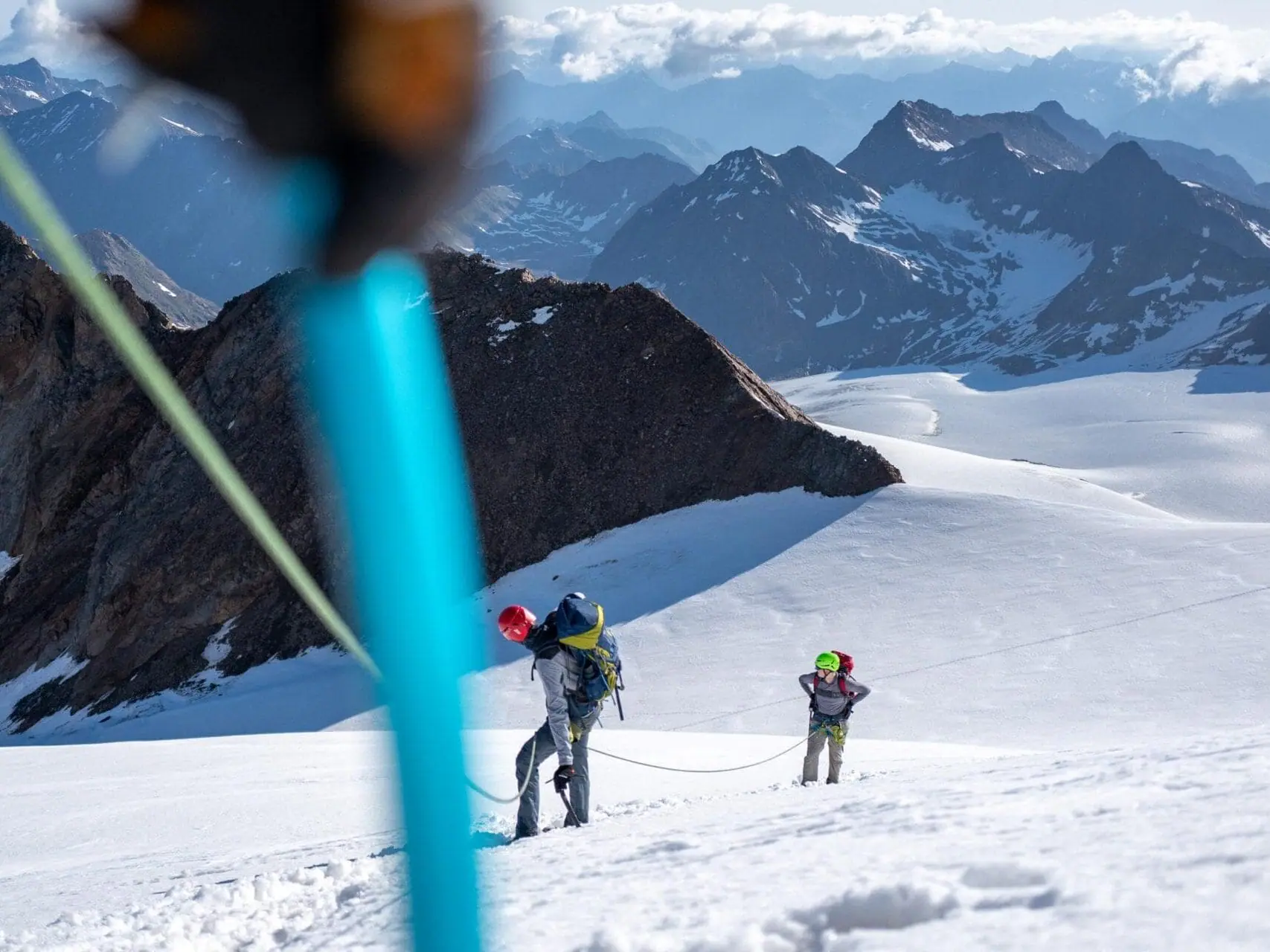 Zwei Bergsteiger auf dem schneebedecktem Jubiläumsgrat mit Bergen im Hintergrund