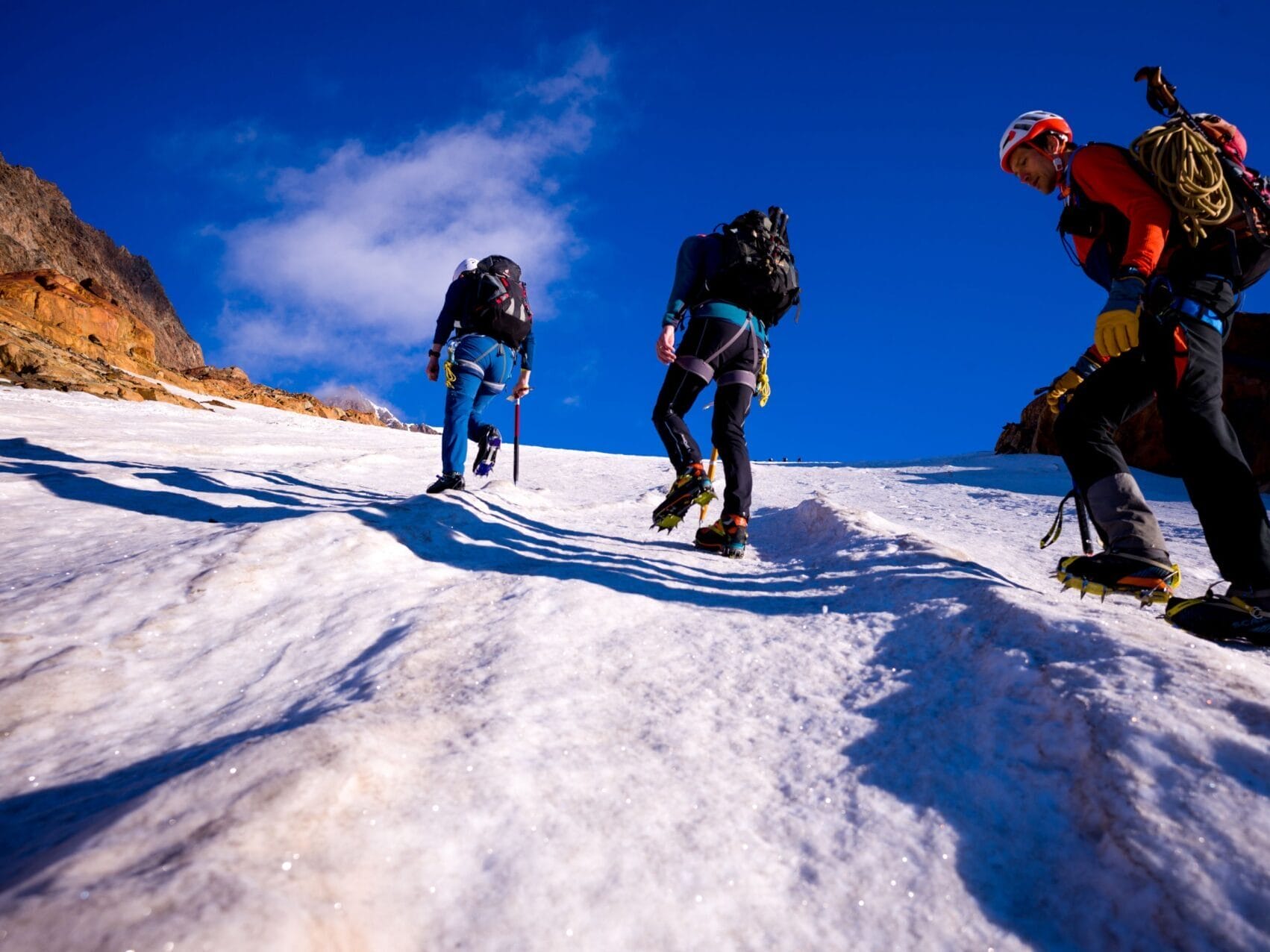 Drei Bergsteiger mit Kletterausrüstung auf schneebedecktem Berg