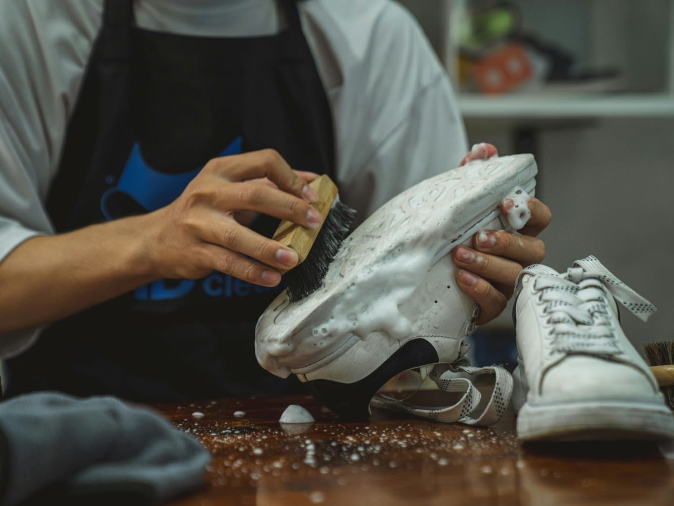 Mann putzt weiße Schuhe von Hand mit einer Schuhbürste